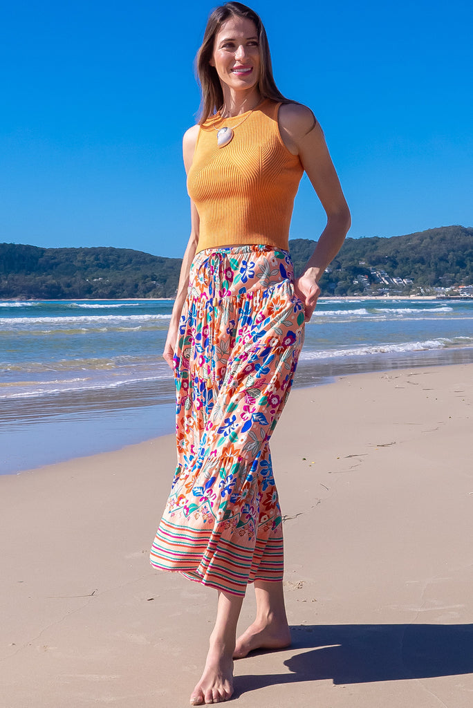 The Cosima Peach Flowers Maxi Skirt is a beautiful peach based skirt with a bright, multicoloured floral print. The skirt featuring a drawstring waist, tiered skirting and side pockets. Made from woven rayon. 