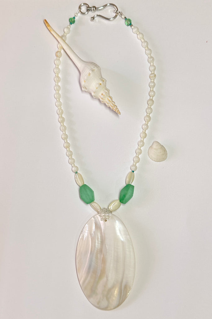 This wonderful Pearly Seas necklace has been designed to use pieces from many countries, the centre piece is a magical slice of mother of pearl shell which has a resin backing, the sea green  side beads are recycled glass from Nigeria in Africa, the pearl shell beads are from The Philippines.