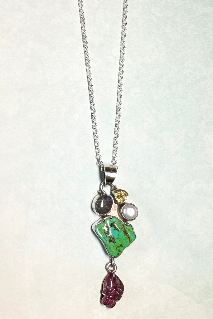 This intriguing pendant is an old piece, it has been handmade in Jaipur, India. It has a central stone of natural turquoise, the stones above are Labradorite, Citrine and natural pearl set in 925 silver. The hanging stone is a pink tourmaline carved into a fish and backed with silver.