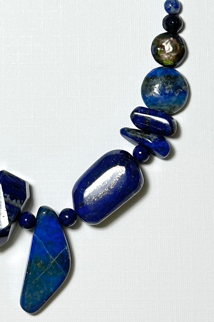 The necklace is made with different shapes of natural blue Lapis Lazuli beads with a highlight of two grey pearls