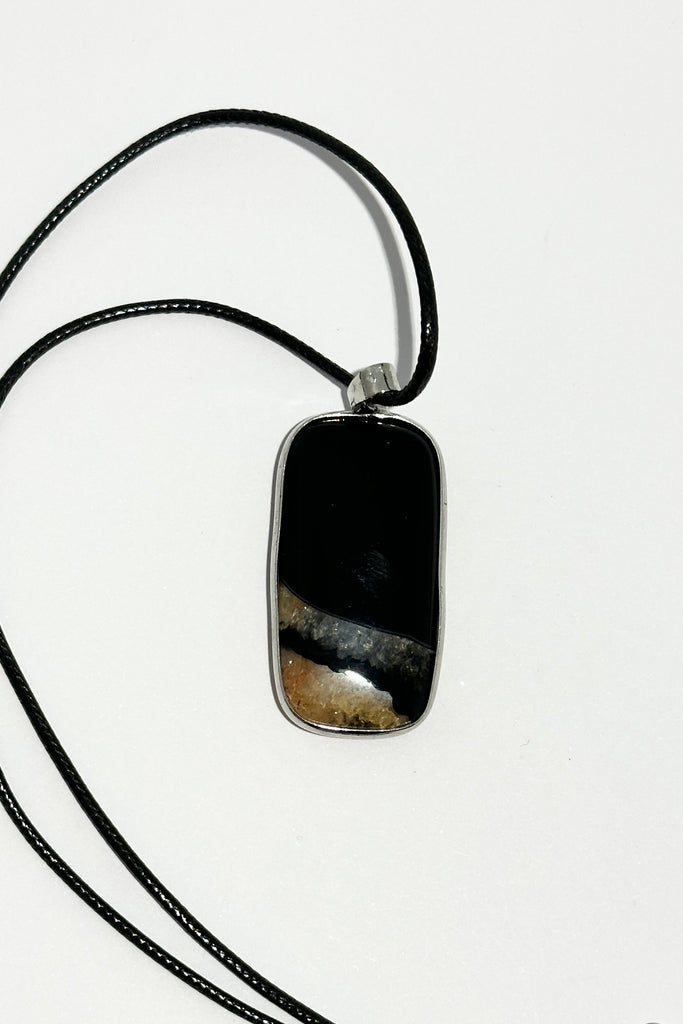 This unique pendant piece is cut from a solid black stone with gorgeous pale peach druzy inclusions at the base, different patterning on both sides.