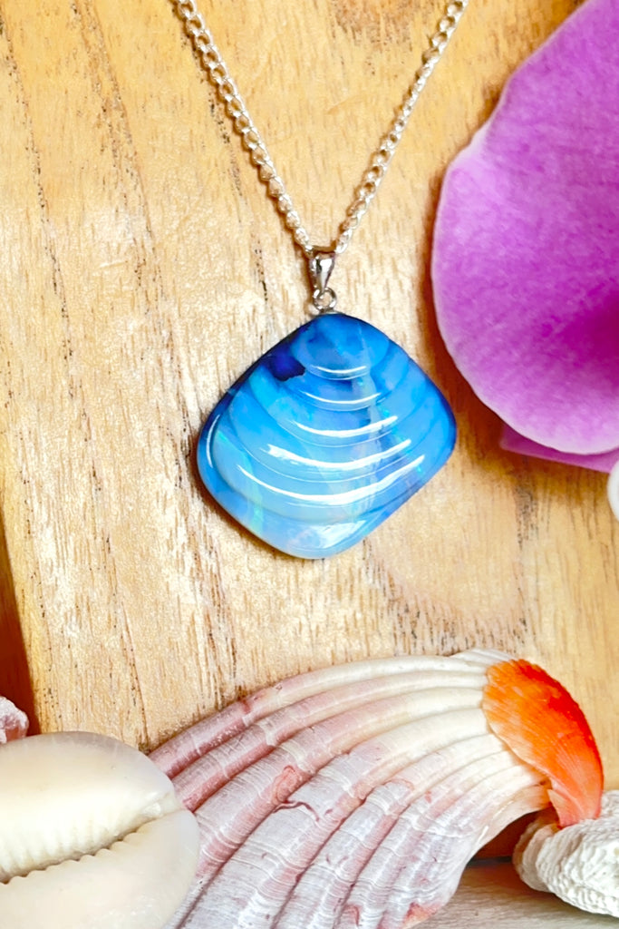 A gorgeous Australian boulder opal pendant carved into in the shape of a Venus shell, it has the look of an ancient shell that has travelled the seas. Misty crystalline mauve with internal lines showing flashes of bright blue, some green and pink.