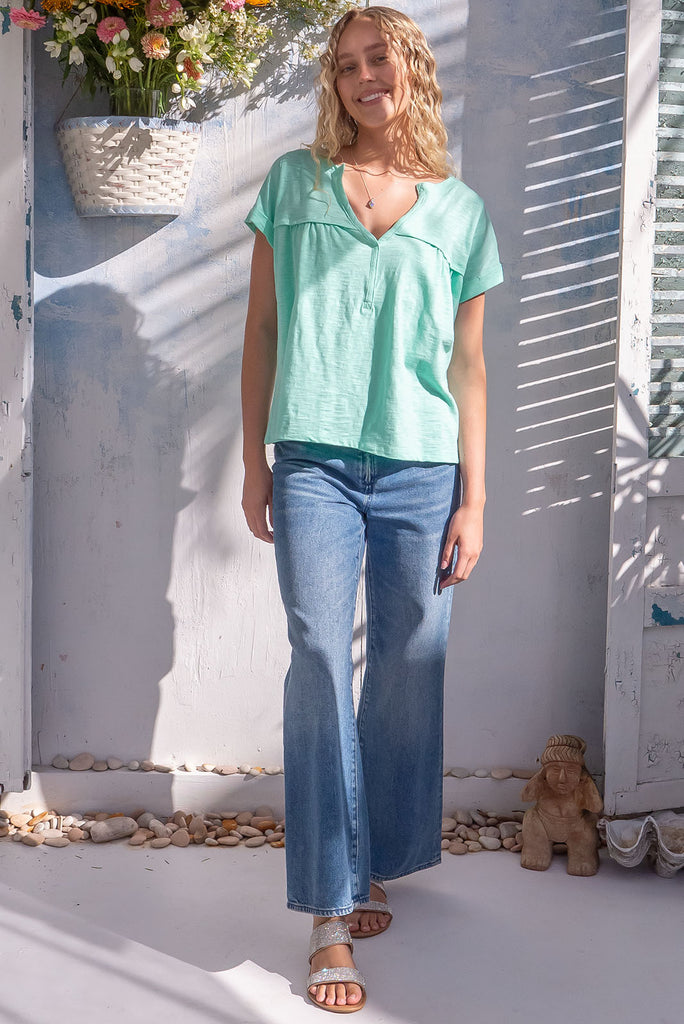 The Lei Tee Sea Green Shirt is a gorgeous pale green t-shirt. The tee features a split neckline, rolled sleeve cuffs, and a gathered bust panel. Made from knit cotton.