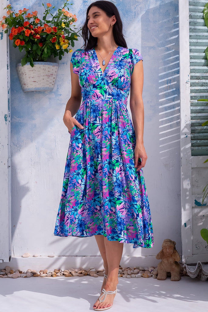 The Lizzie Leaf Blue Midi Dress is a beautiful blue midi dress with a vibrant leaf print. The dress features a basque waist, feminine cut and gathered bust. Made from 100% rayon. 