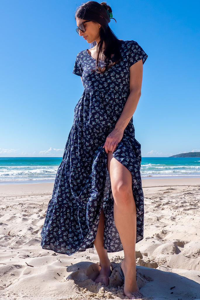 The Lucky Lulu Inky Sprinkle Maxi Dress is a beautiful tiered maxi dress with a navy blue base and small white floral print. This dress features a scooped neckline, adjustable waist tabs, side pockets and a wide tiered skirt. Made a woven blend of cotton and rayon.