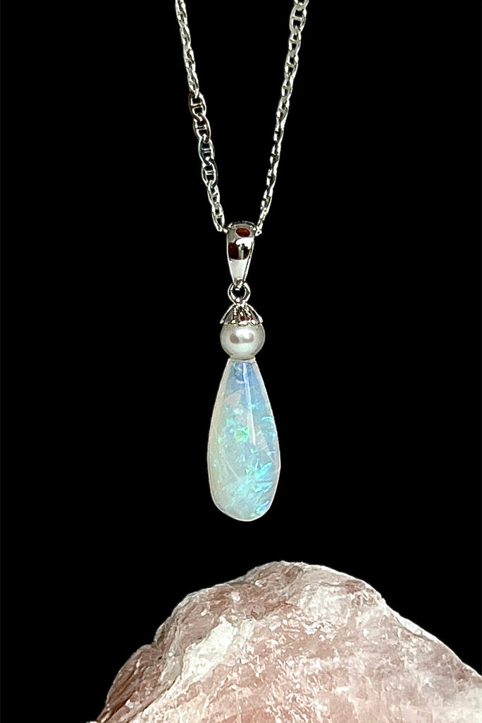 An opal pendant featuring a droplet of Australian crystal opal cut and polished to reveal the flecks of colour through the stone. A one of a kind opal. This piece has soft mystical colouring, flecks of green, blue and mauve.