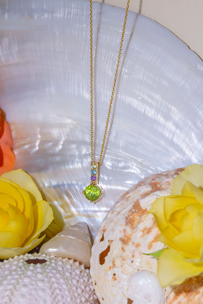 A pretty sparkling pendant featuring a round faceted Peridot gemstone set in 9ct gold vermeil, the accent is a bar of tiny amethyst, peridot and blue topaz accent stones.