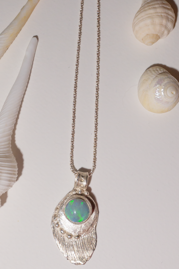 The pendant is solid silver, it is cast from a shard of old sea worn shell and has a beautiful Australian opal set onto the front. This pendant is handmade and totally unique