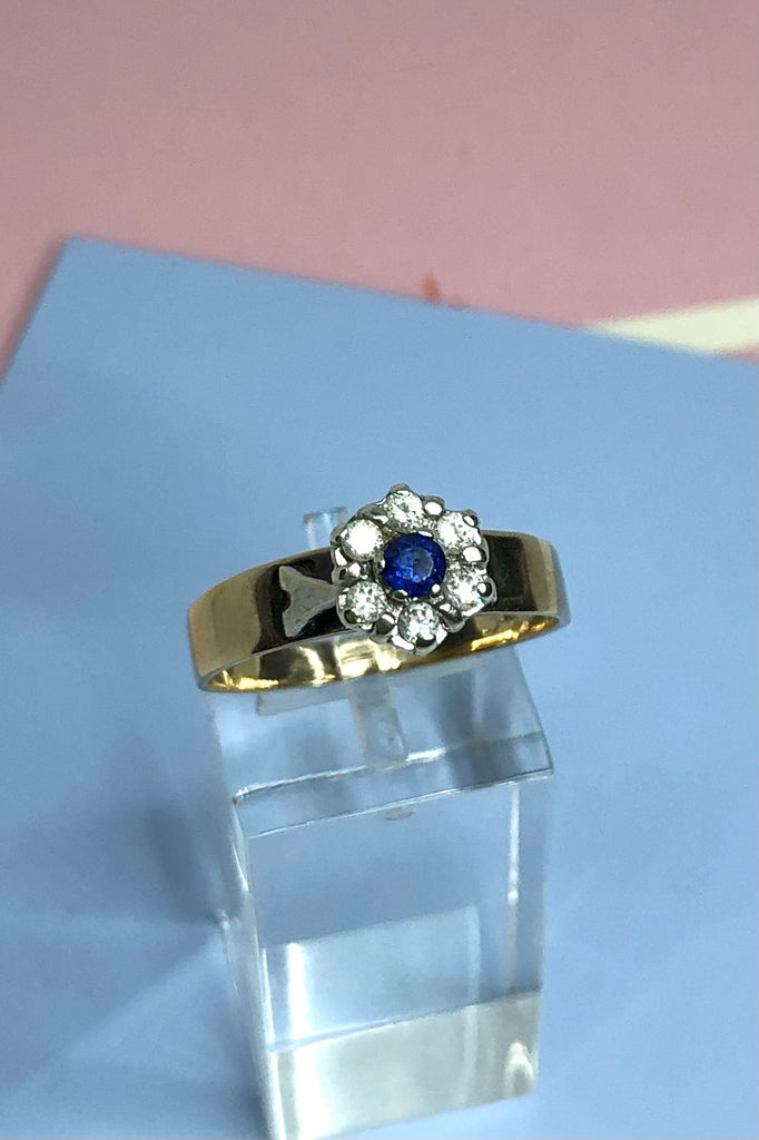 This Vintage ring features a very high setting, a small clear blue sapphire is halo set with six old cut white topaz. 