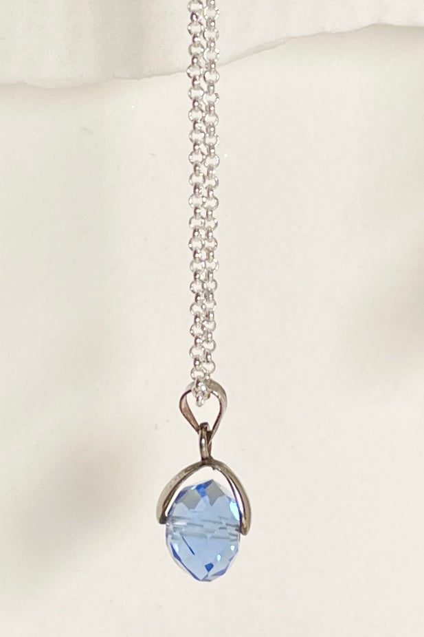 A dainty crystal bead hung from a silvery bail. 