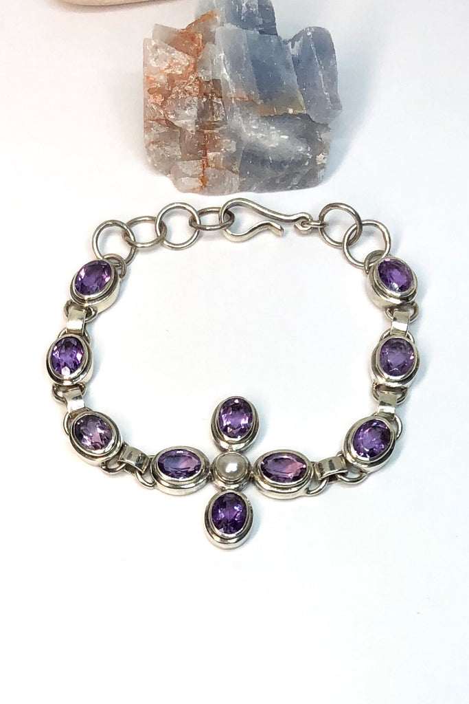 each faceted Amethyst gemstone in the Bracelet Amethyst Pearl has been cut to enhance the gorgeous mauve colour. Each of the ten stones  has been individually set and rim set into 925 silver.  The centre piece is a flower with a pearl centre.