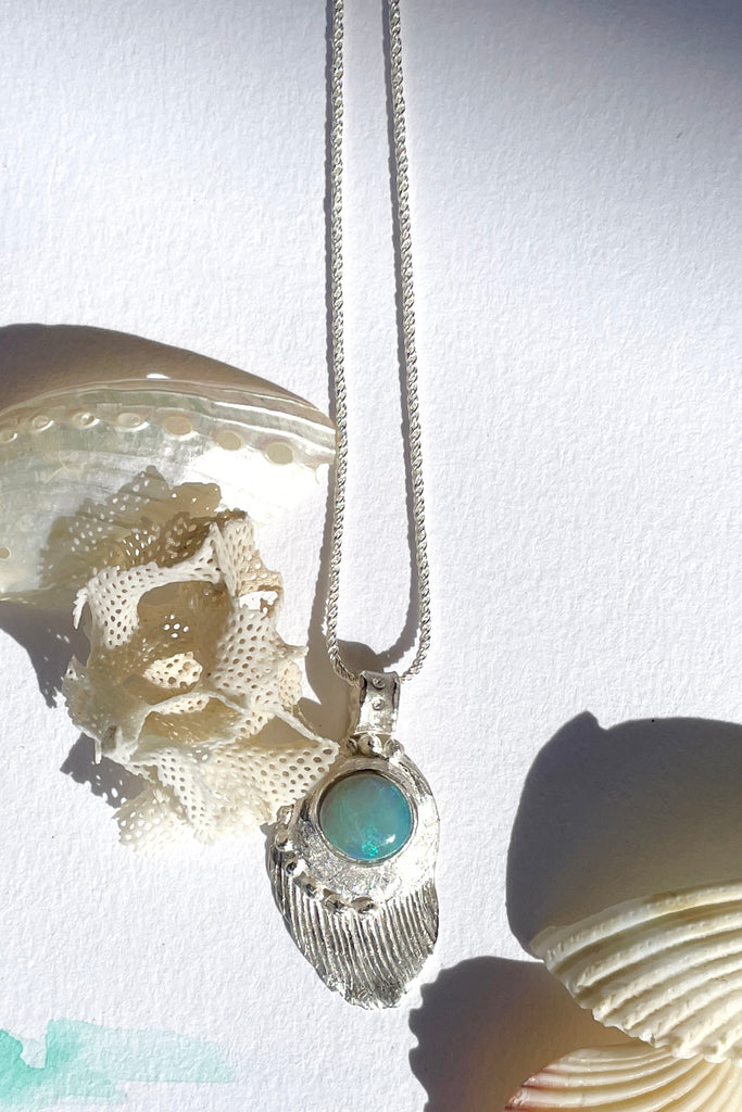 The pendant is solid silver, it is cast from a shard of old sea worn shell and has a beautiful Australian opal set onto the front. This pendant is handmade and totally unique