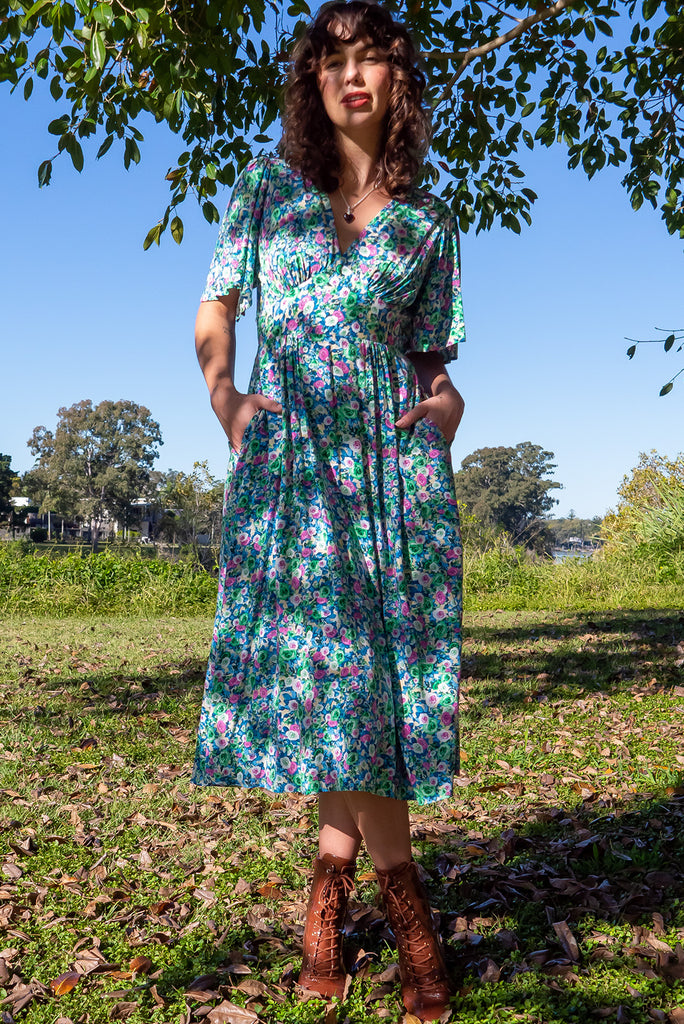 The Annie Tinker Blue Midi Dress is beautiful blue dress with a floral print in blues, greens and pink. The dress features flutter sleeves, a deep v neckline, fitted basque waist with gathered bust, elastic shirring at back waist, side pockets and is made from woven 100% rayon.