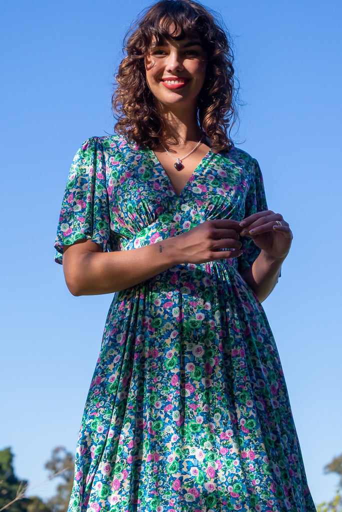 The Annie Tinker Blue Midi Dress is beautiful blue dress with a floral print in blues, greens and pink. The dress features flutter sleeves, a deep v neckline, fitted basque waist with gathered bust, elastic shirring at back waist, side pockets and is made from woven 100% rayon.