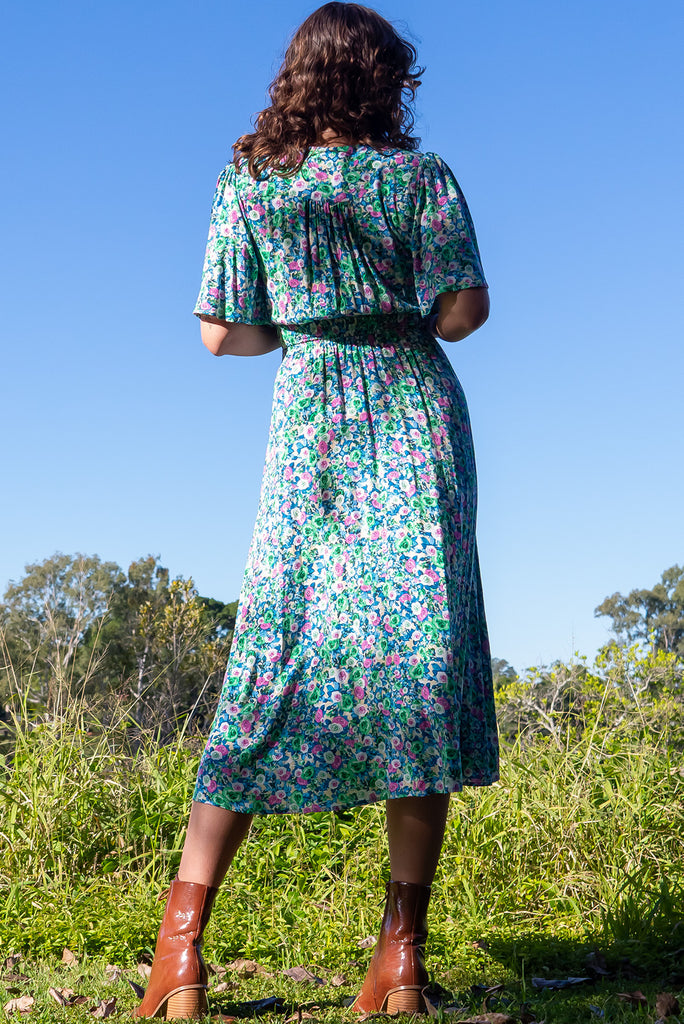 The Annie Tinker Blue Midi Dress is beautiful blue dress with a floral print in blues, greens and pink. The dress features flutter sleeves, a deep v neckline, fitted basque waist with gathered bust, elastic shirring at back waist, side pockets and is made from woven 100% rayon.