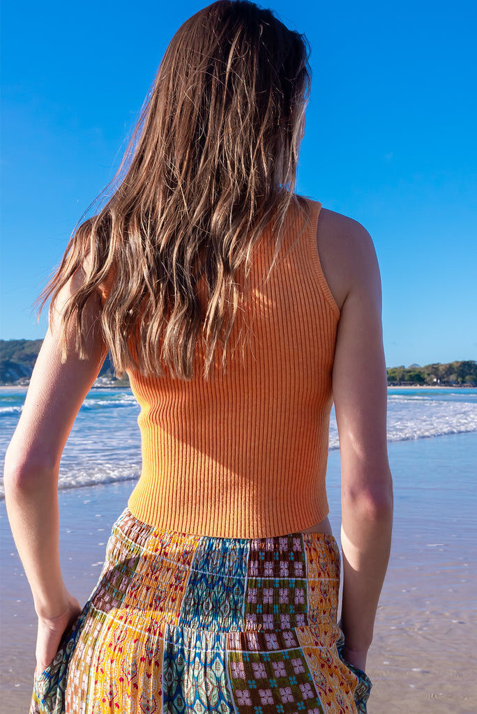 The Astro Mango Knit Tank Top is a luxurious orange tank top. The tank top features a high neck, stretchy knit fabric, ribbed texture and is fitted. 