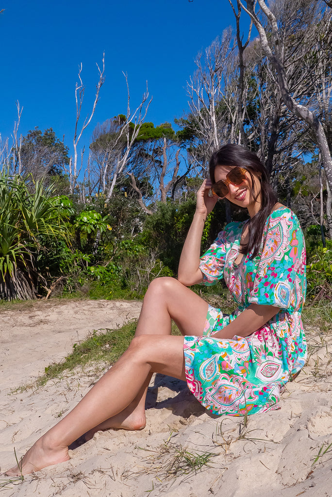The Collette Green Daze Mini Dress is a gorgeous green based mini dress with a large, abstract leaf print. The dress features functional buttons from front chest to waist, adjustable drawstring at either side of waist, v-neckline, 3/4 sleeves, and side pockets. Made from woven rayon.