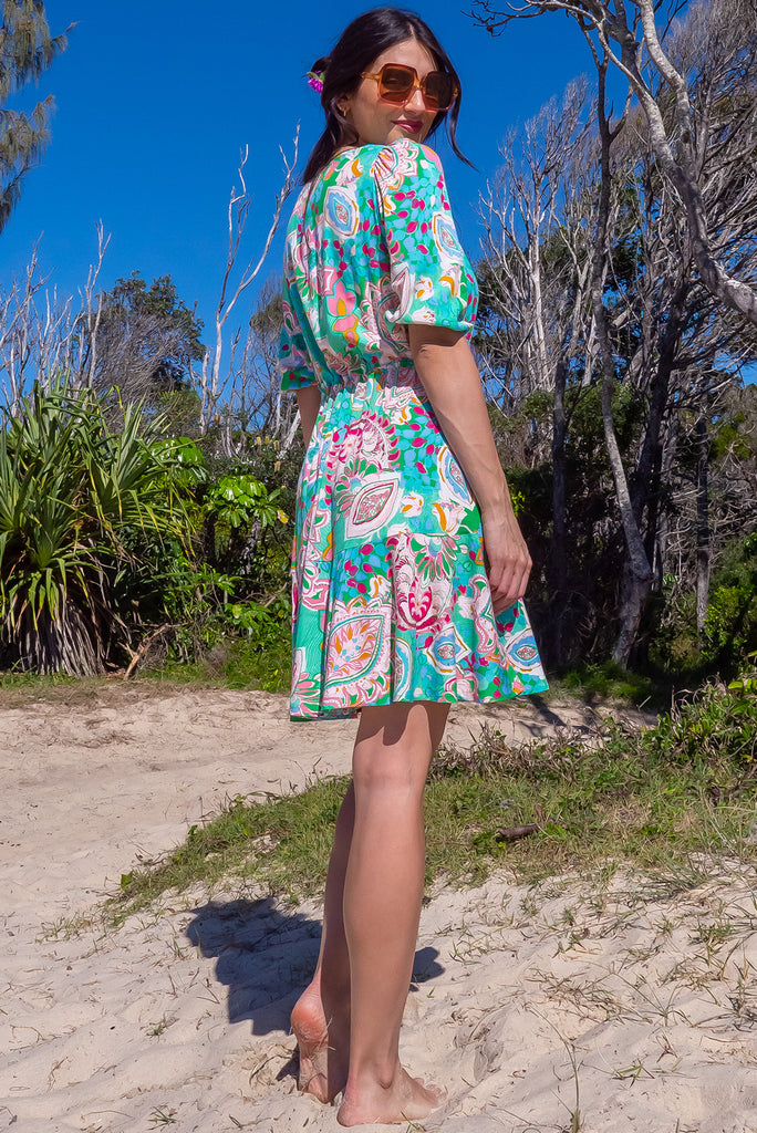 The Collette Green Daze Mini Dress is a gorgeous green based mini dress with a large, abstract leaf print. The dress features functional buttons from front chest to waist, adjustable drawstring at either side of waist, v-neckline, 3/4 sleeves, and side pockets. Made from woven rayon.