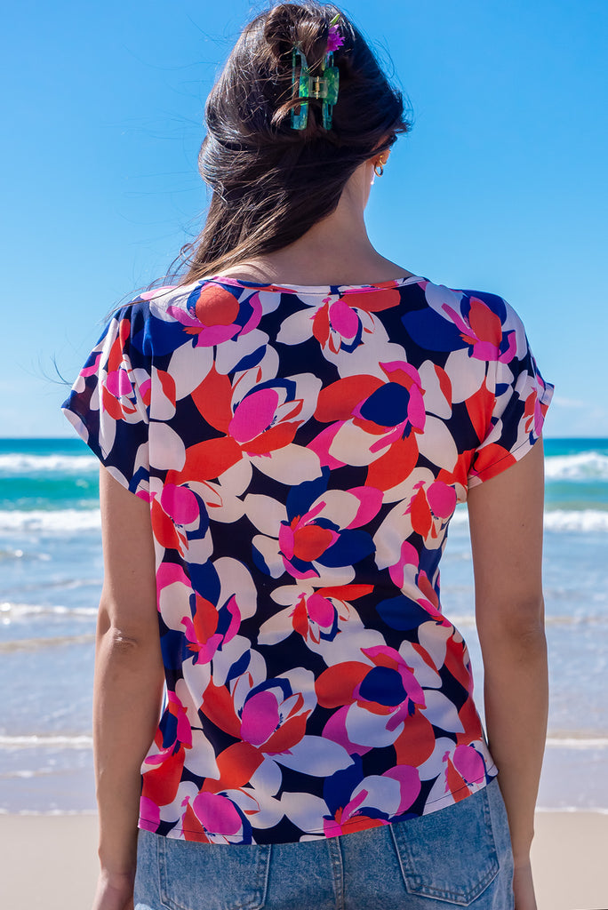The Day Tripper Bold Summer Top is a gorgeous shirt with a bold floral print in pink, orange and blues. The top features a scooped neckline, lace insert across the chest, cap sleeves, and a small split in the side seams. Made from woven rayon.
