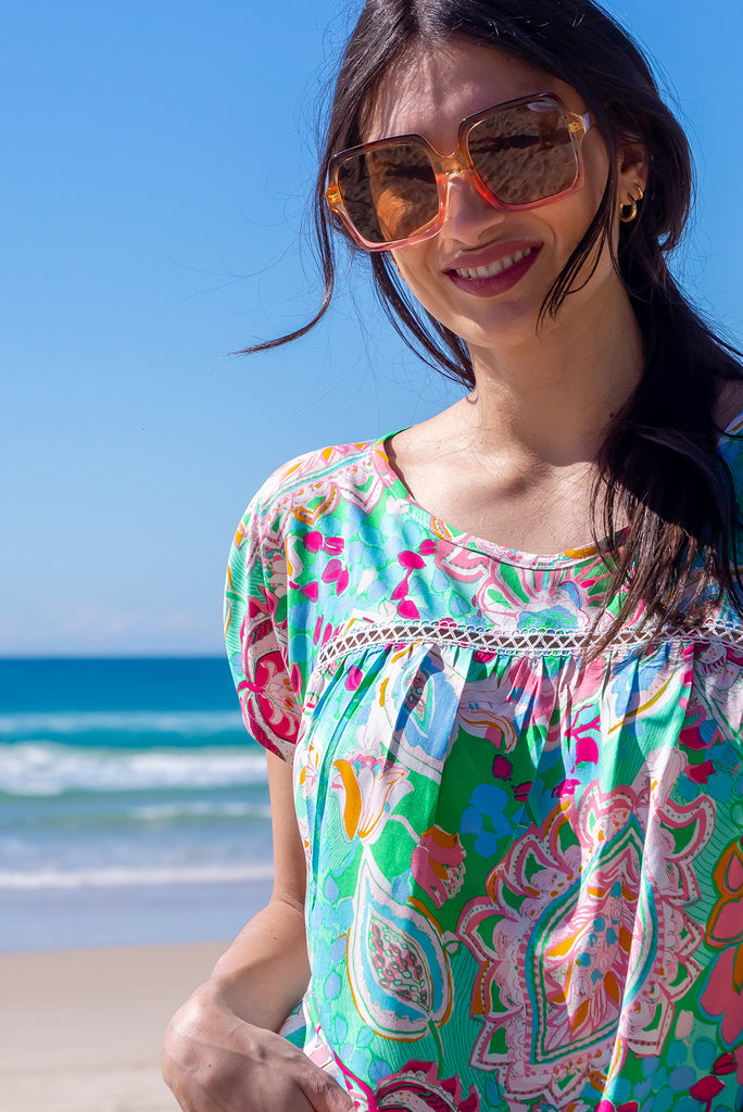 The Day Tripper Green Leaf Top is a gorgeous green t-shirt with a large, abstract leaf print. The top features a scooped neckline, lace insert across the chest, cap sleeves, and a amall split in the side seams. Made from woven rayon.