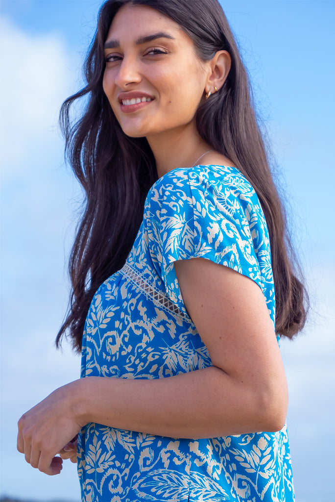 The Day Tripper Top Blue Atoll is a beautiful blue based shirt with a cream paisley print. The top features a scooped neckline, lace insert across the chest, cap sleeves, and a small split in the side seams. Made from woven rayon.