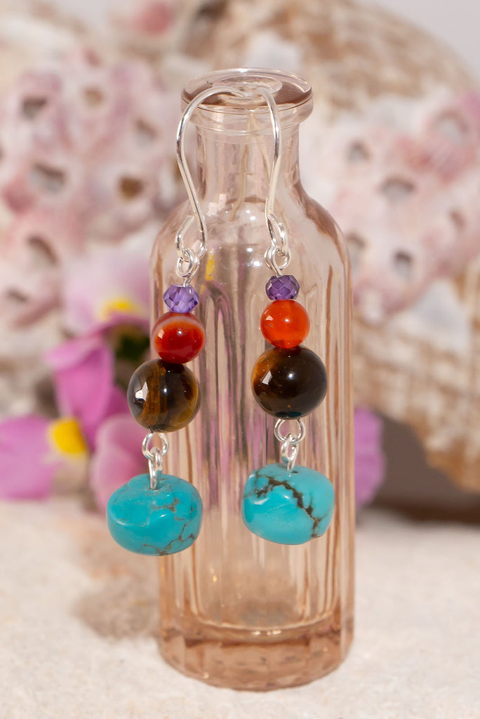 A desert somewhere with the vast blue sky, ancient rocks and a tiny mauve flower. Small drop earrings influenced by nature.