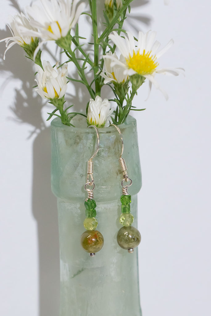 Drawing inspiration from the lush colours of nature, these gemstone droplet earrings showcase a trio of vibrant green gems, evoking the beauty of a forest in every detail.