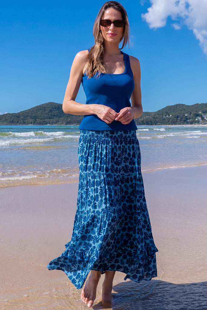 The Echo Blue Palms Maxi Skirt is a beautiful blue maxi skirt with a dark blue leaf silhouette  print. The skirt features an elasticated waistband, tiering and side pockets. Made from crinkle rayon.