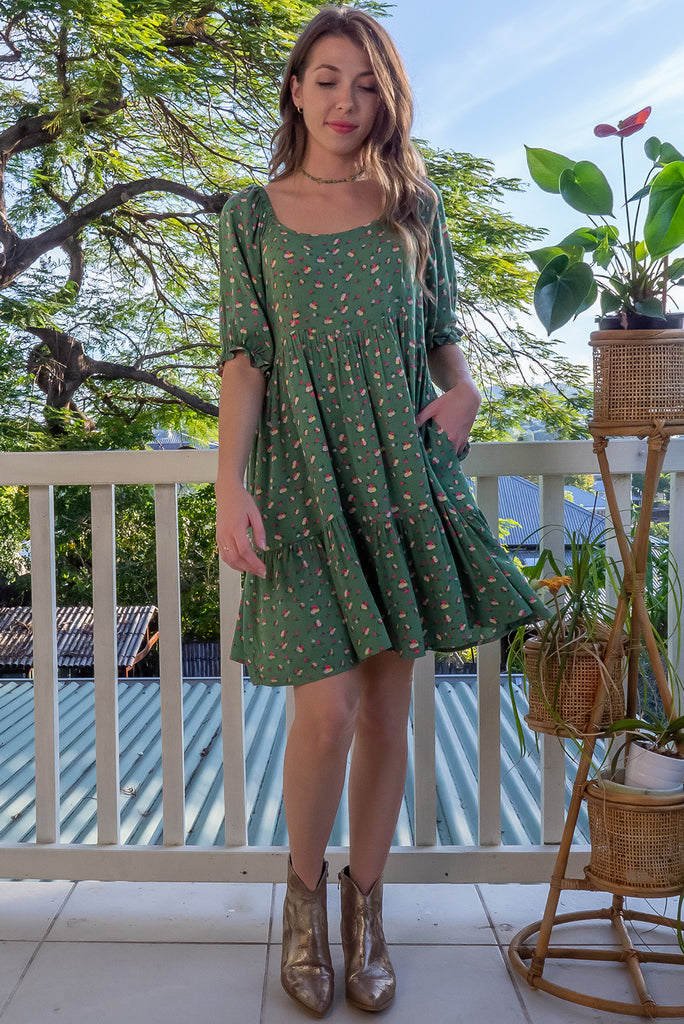 The Emelia Green Flowers Short Dress is a gorgeous green mini dress with a small white and pink floral print. The mini dress features 3/4 sleeves with elastic cuffs, tiered skirting and side pockets. Made from a woven blend of crinkle rayon.