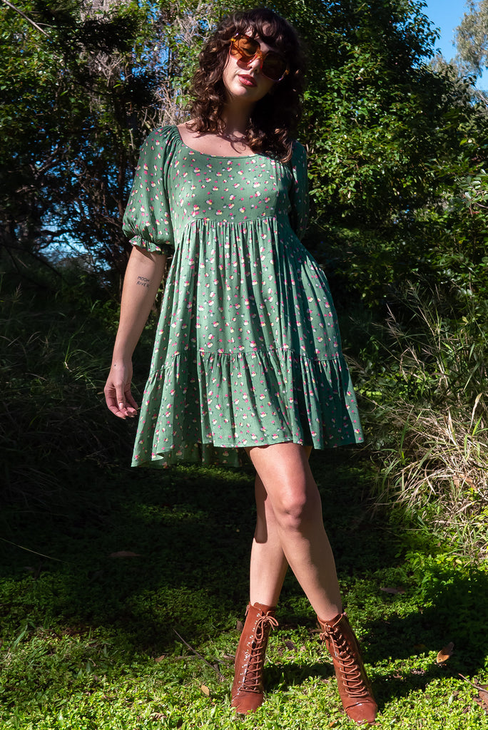 The Emelia Green Flowers Short Dress is a gorgeous green mini dress with a small white and pink floral print. The mini dress features 3/4 sleeves with elastic cuffs, tiered skirting and side pockets. Made from a woven blend of crinkle rayon.