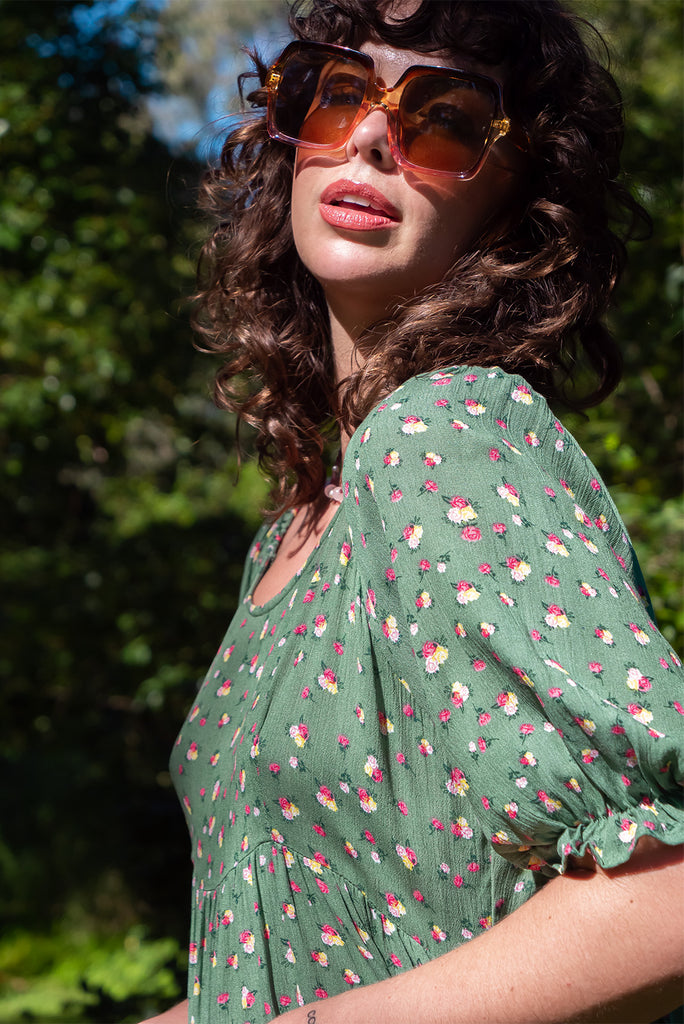 The Emelia Green Flowers Short Dress is a gorgeous green mini dress with a small white and pink floral print. The mini dress features 3/4 sleeves with elastic cuffs, tiered skirting and side pockets. Made from a woven blend of crinkle rayon.