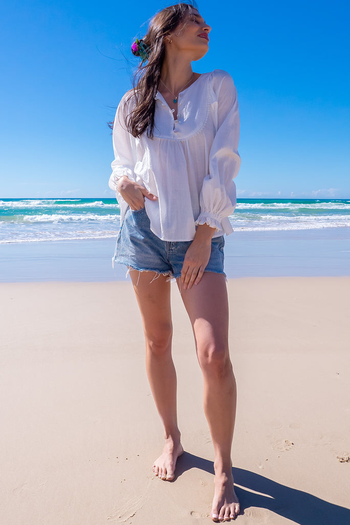 The Emmylu White Cotton Boho Blouse is a beautiful white blouse. The blouse features a yoke neckline with functional buttons, long flowy sleeves with elasticated cuffs, and a slightly longer back. Made from woven 100% cotton. 