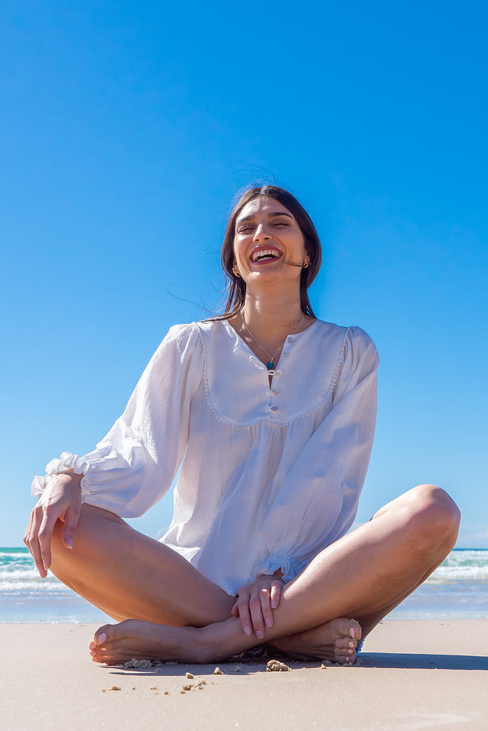The Emmylu White Cotton Boho Blouse is a beautiful white blouse. The blouse features a yoke neckline with functional buttons, long flowy sleeves with elasticated cuffs, and a slightly longer back. Made from woven 100% cotton. 