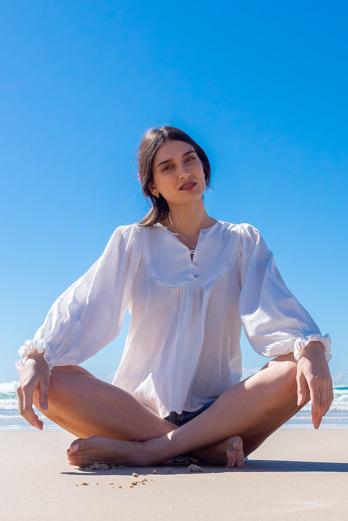 The Emmylu White Cotton Boho Blouse is a beautiful white blouse. The blouse features a yoke neckline with functional buttons, long flowy sleeves with elasticated cuffs, and a slightly longer back. Made from woven 100% cotton. 