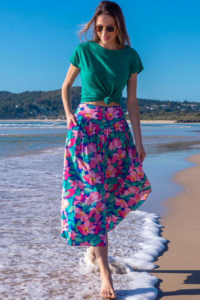 The Flirt Flora Button Front Maxi Skirt is a beautiful blue based skirt with a bright, pink and green floral print. The skirt features a waist yoke with blue piping, functional buttons from waist to hem, elasticated back of waist, and side pockets. Made from 100% rayon. 