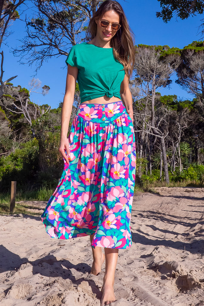 The Flirt Flora Button Front Maxi Skirt is a beautiful blue based skirt with a bright, pink and green floral print. The skirt features a waist yoke with blue piping, functional buttons from waist to hem, elasticated back of waist, and side pockets. Made from 100% rayon. 