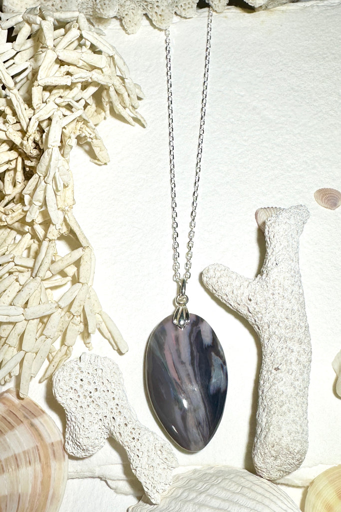 his opal pendant is a curious piece, the dark landscape has hints of pink running deep within the stone, there is a sunlight flash of green gold on the top corner, a hidden world.