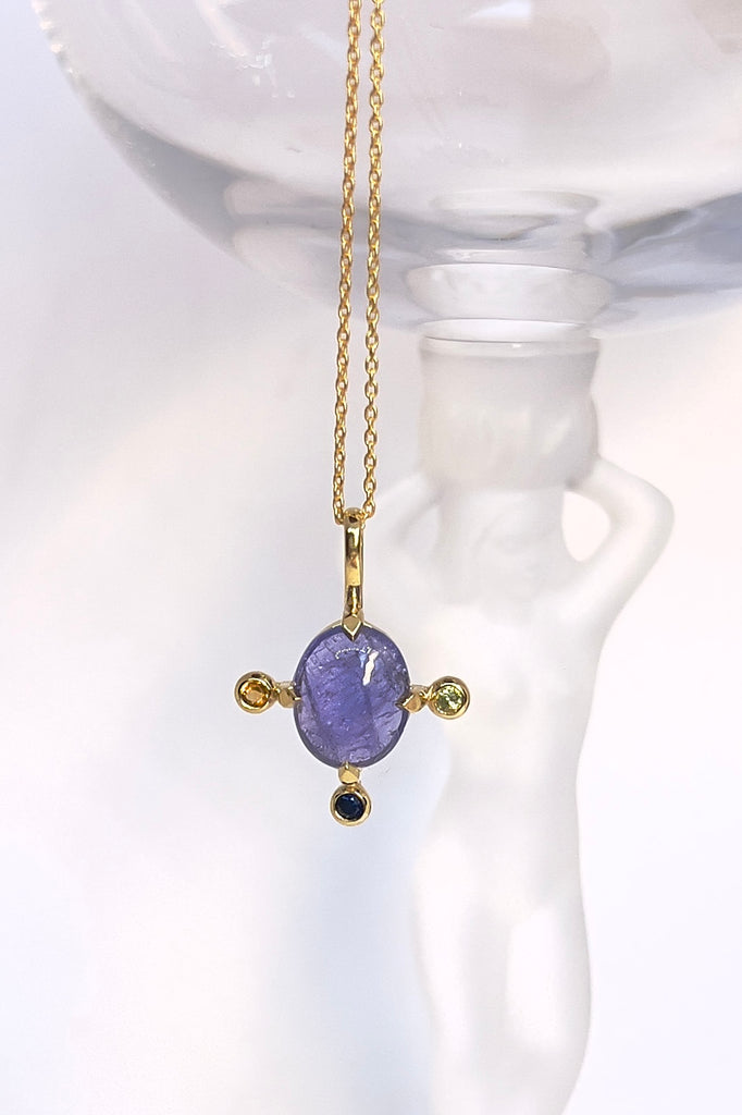 The pendant and chain are 9ct gold vermeil on a base of 925 silver, the gold is 2.5microns thick so will never rub or discolor An oval cabochon cut Tanzanite gemstone set in 9ct gold vermeil. Side stones are blue green and yellow sapphires gemstones.