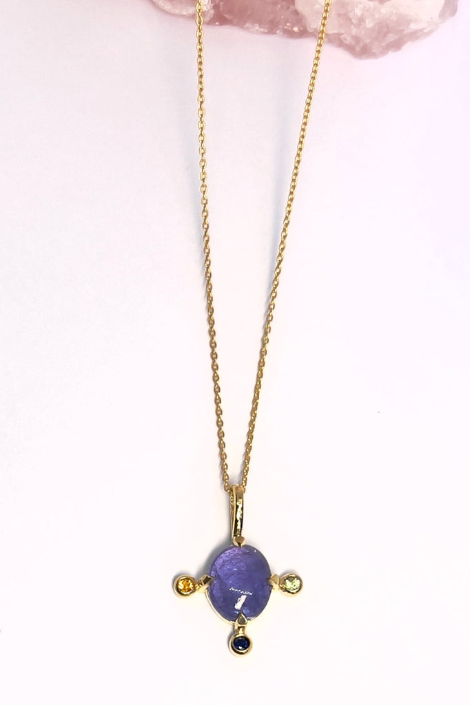 The pendant and chain are 9ct gold vermeil on a base of 925 silver, the gold is 2.5microns thick so will never rub or discolor An oval cabochon cut Tanzanite gemstone set in 9ct gold vermeil. Side stones are blue green and yellow sapphires gemstones.