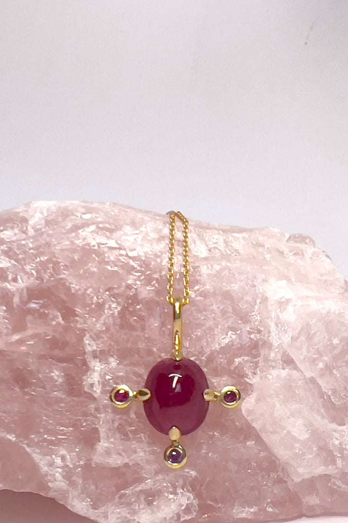 The pendant and chain are 9ct gold vermeil on a base of 925 silver, the gold is 2.5microns thick so will never rub or discolor An oval cabochon Ruby gemstone set in 9ct gold vermeil. Side stones are Sapphires. This pendant is a perfect celebration of femininity and chic. Pendant is 2.5cm long. Chain is gold vermeil