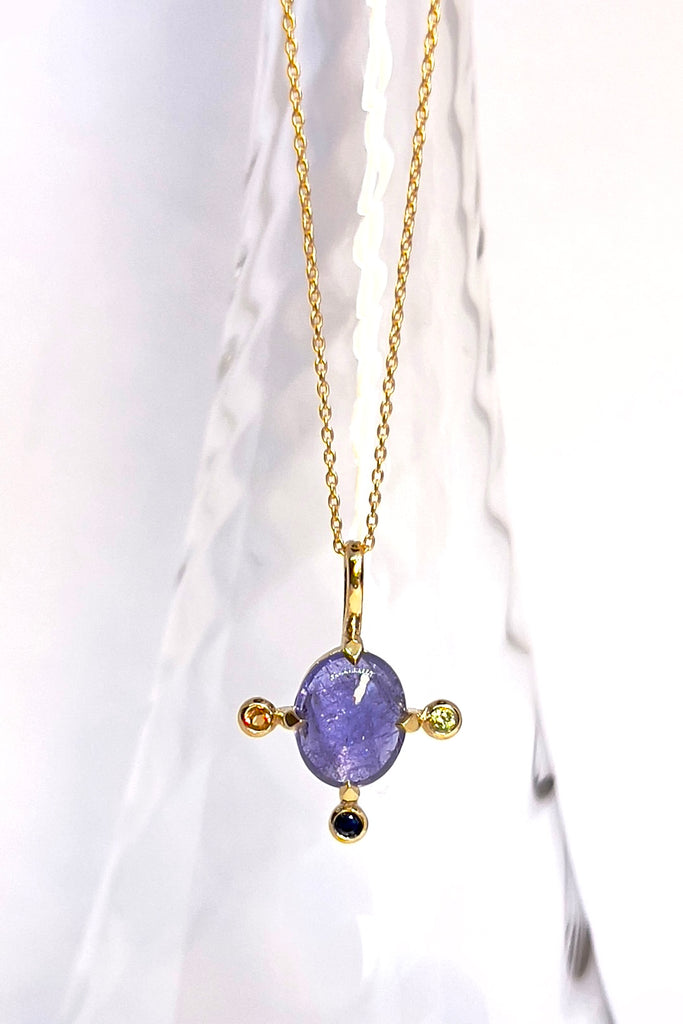 The pendant and chain are 9ct gold vermeil on a base of 925 silver, the gold is 2.5microns thick so will never rub or discolor An oval cabochon cut Tanzanite gemstone set in 9ct gold vermeil. Side stones are blue green and yellow sapphires gemstones.