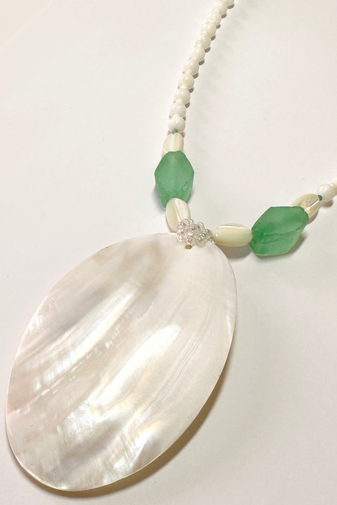 This wonderful Pearly Seas necklace has been designed to use pieces from many countries, the centre piece is a magical slice of mother of pearl shell which has a resin backing, the sea green  side beads are recycled glass from Nigeria in Africa, the pearl shell beads are from The Philippines.