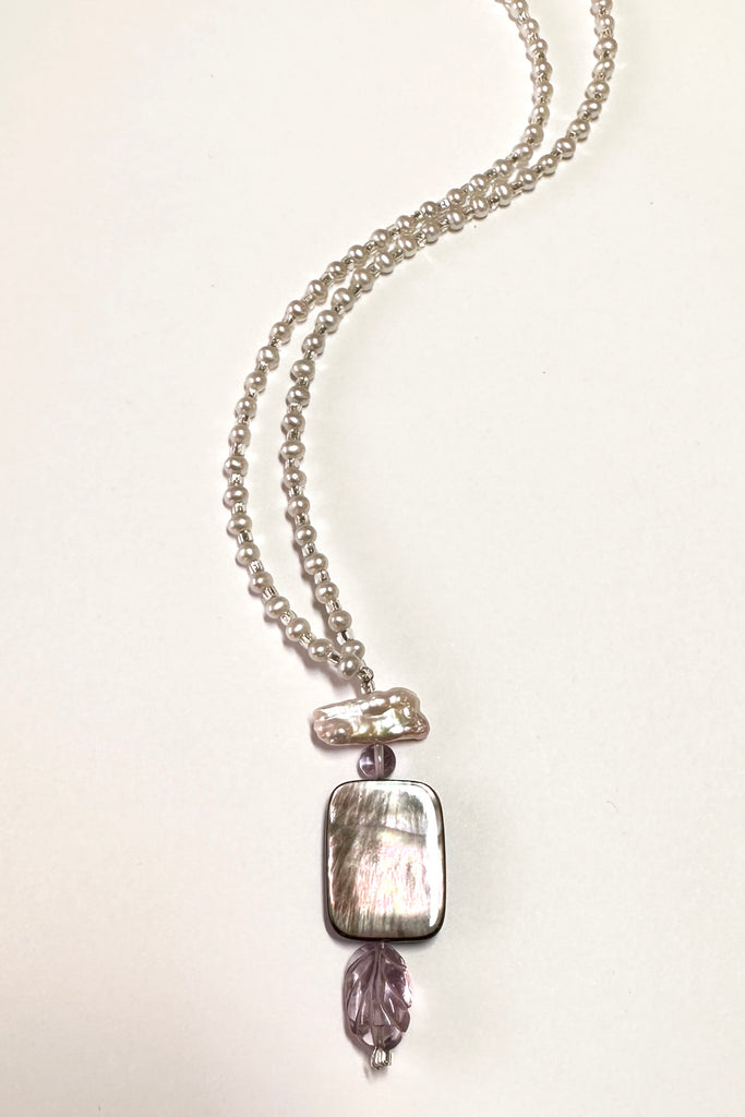 This pretty necklace is a one off piece made exclusively for Mombasa Rose Boutique. The centrepiece is of silvery grey mother of pearl shell with a carved Amethyst leaf below.  The necklace is of cream natural pearls.