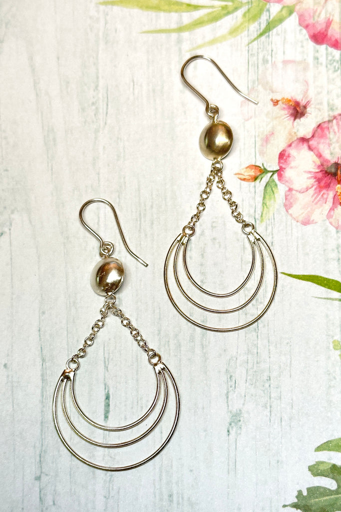 A lovely delicate handmade silver earring, the circle is a finely hammered dome. Suspended from the two chains swings a swoop of three tiny silver wires. The inspiration for this design was the wire work of Africa. 