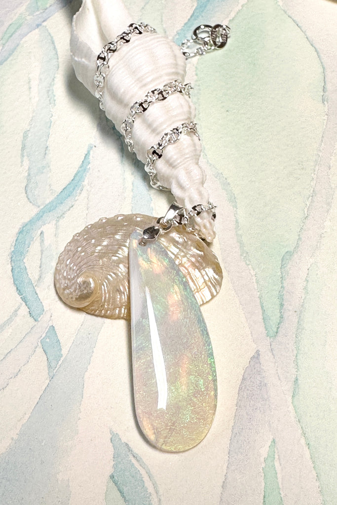 An opal pendant featuring a beautiful delicate whisper of of Australian crystal opal cut and polished to reveal the flecks of colour through the stone. A one of a kind opal. This piece has soft mystical colouring, flecks of green, blue and a little mauve. Australian Crystal Opal.