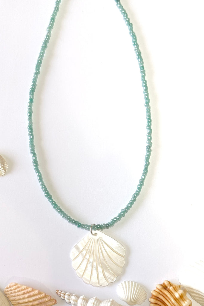 this scallop shape hand carved from Mother of Pearl shell all carry the distinctive marks of the artist who created them, no two shells are ever alike,  strung on pearlescent pale blue glass beads.