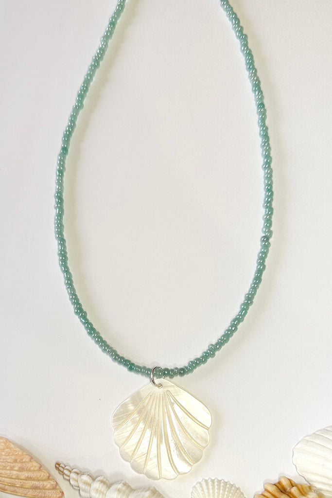 this scallop shape hand carved from Mother of Pearl shell all carry the distinctive marks of the artist who created them, no two shells are ever alike,  strung on pearlescent pale blue glass beads.