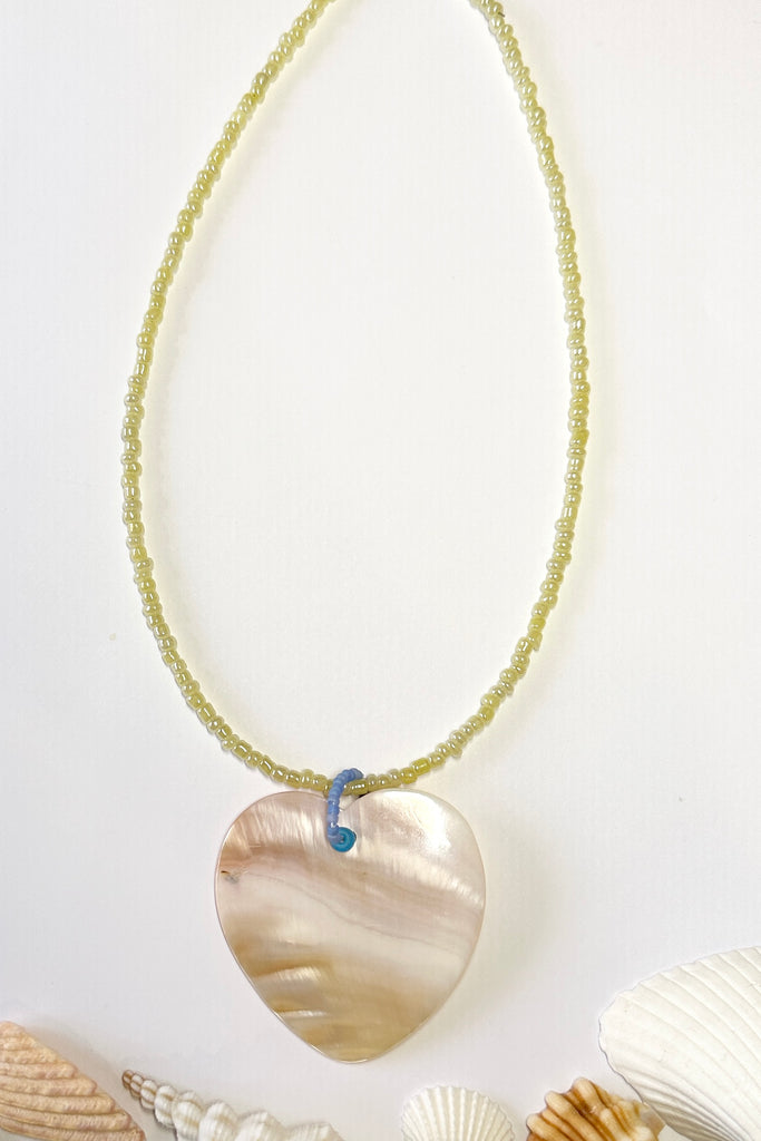 this gorgeous heart is hand carved from Mother of Pearl shell, each heart carries the distinctive marks of the artist who created it, no two shells are ever alike,  strung on pearlescent pale lemon yellow glass beads. 