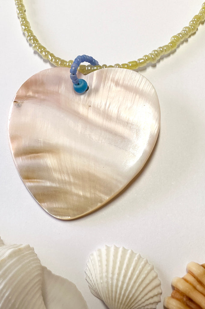 this gorgeous heart is hand carved from Mother of Pearl shell, each heart carries the distinctive marks of the artist who created it, no two shells are ever alike,  strung on pearlescent pale lemon yellow glass beads. 