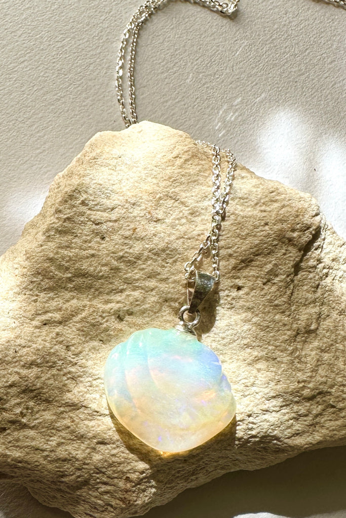 An opal pendant featuring a tiny carved seashell in Australian crystal opal. This is a very softly coloured piece with mauve, green and pink. A one of a kind opal. This piece has soft misty colouring, flecks of green, blue and mauve. Australian Crystal Opal.